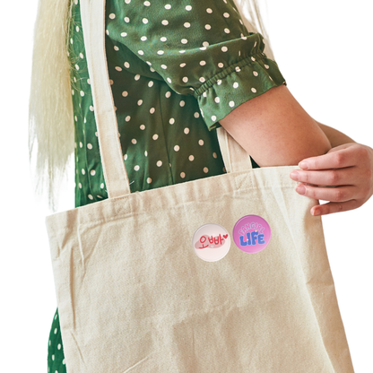 Person holding a beige tote bag with colorful stickers, wearing a green polka dot shirt. K-Drama Mood Korean Phrase Pin Set (4pcs) – Oppa, Gwaenchana & Fangirl Life